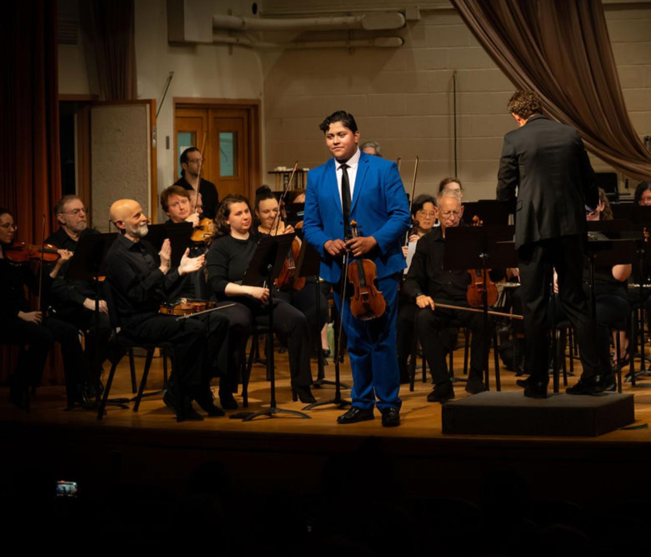 Jonathan Zapuche acknowledging applause with the Wilmington Community Orchestra